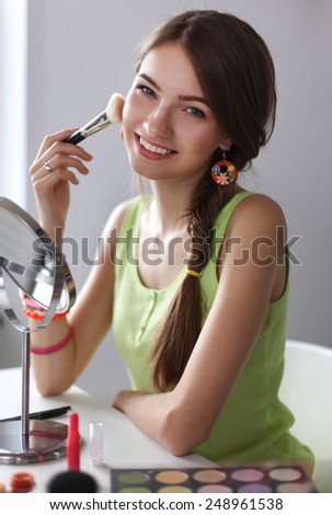 Young beautiful woman making make-up near mirror,sitting at the desk