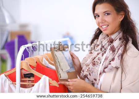 Beautiful young stylist woman near rack with hangers