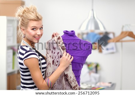 Smiling fashion designer standing near mannequin in office