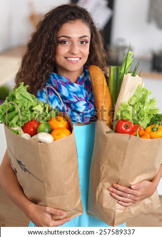 Young woman holding grocery shopping bag with vegetables Standing in the kitchen.