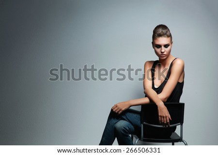 Beautiful woman sitting a chair, isolated on gray background