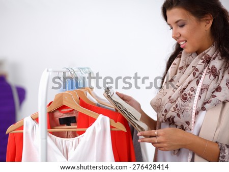 Beautiful young stylist woman near rack with hangers