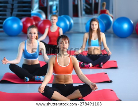 Sporty people sitting on exercise mats at a bright fitness studio