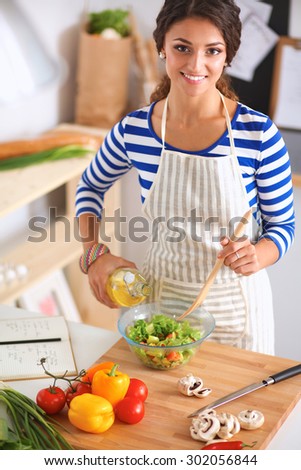 Smiling young woman mixing fresh salad
