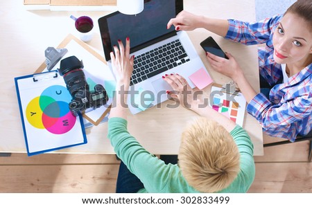 Two women photographer sitting on the desk with laptop