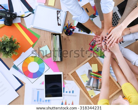 Team of office workers putting their hands together in a symbol of unity