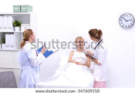 Smiling female doctor with a folder in uniform standing at hospital near patient