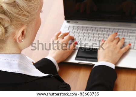 A portrait of a businesswoman sitting at a desk with a laptop,  back view