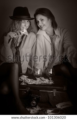 Portrait of two beauty girls in man shirts with money, suitcase and brandy soft sepia effect