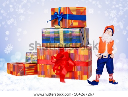 Little christmas elf standing near big gift boxes on the snow background