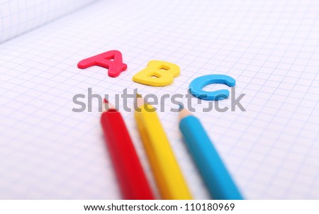 Close up image alphabet letters ABC on copybook page with colored pencils