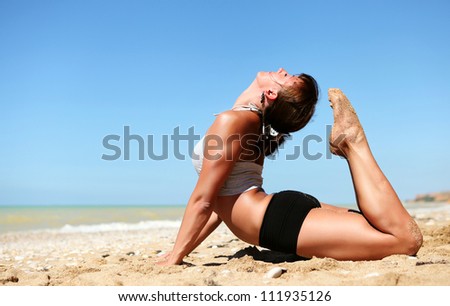 Yoga practice. Young flexible woman doing full cobra yoga pose at the beach