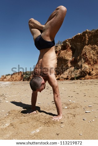 Yoga practice. Man doing balancing handstand with lotus yoga position