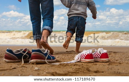 Close up image father and son legs walk at the seaside