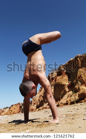 Yoga practice. Man doing vertical handstand with legs in  lotus position