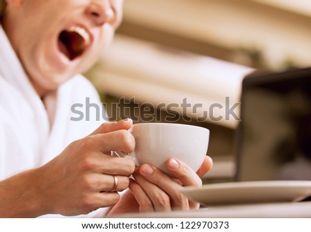 Closeup image yawning sleepy man with cup of coffee in hand