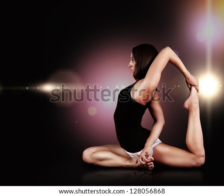 A beautiful young woman performs a yoga exercise on a dark purple background