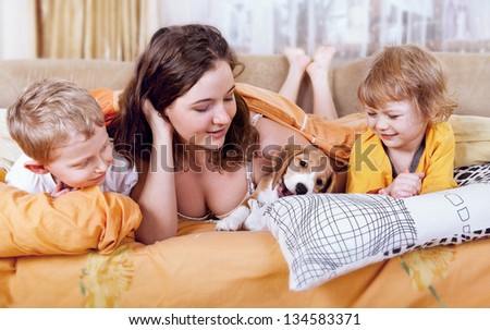 Morning time scene. Children  with beagle puppy in the bed