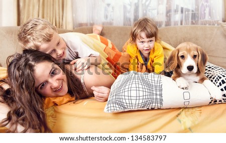 Happy children playing with beagle puppy in bed