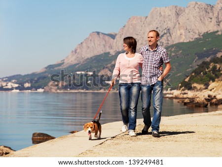 Happy couple walking with beagle puppy at the seacoast
