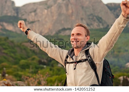 Happy man with victory gesture hands on the mountain view landscape