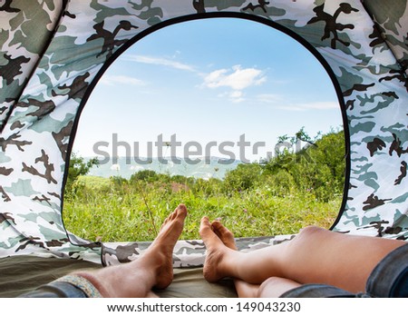 Closeup image couple legs lying together near open door tourist tent