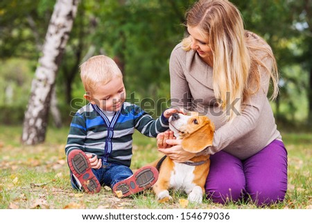 Pregnant mother with her little son and pet on walk in park