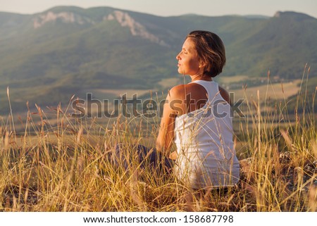 Sitting in meditation pose woman enjoyed with gently shining sunrise