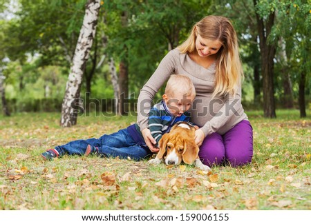 Pregnant mother with her son fun playing with their pet in park