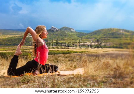 Beautiful slim woman has yoga practice in mountain terrain