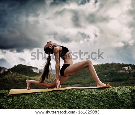 Slim young woman makes warrior yoga pose