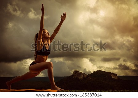 Young woman makes sun salutation yoga pose