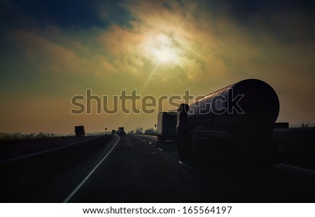 Gasoline tanker rides the highway in the evening sun rays