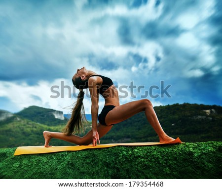 Slim young woman makes warrior yoga pose