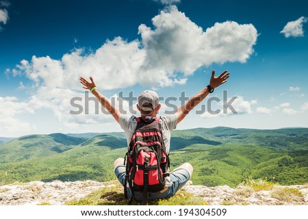 Man hiker greeting rich nature on the top of mountain