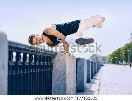 Young man break dancer makes element of dance on the railing
