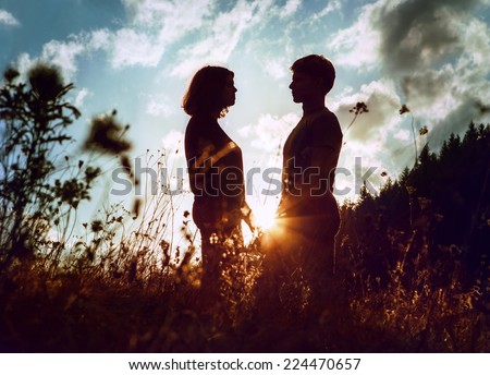 Sunrise silhouettes of two in love young people