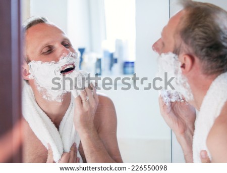 Shaving man near the mirror