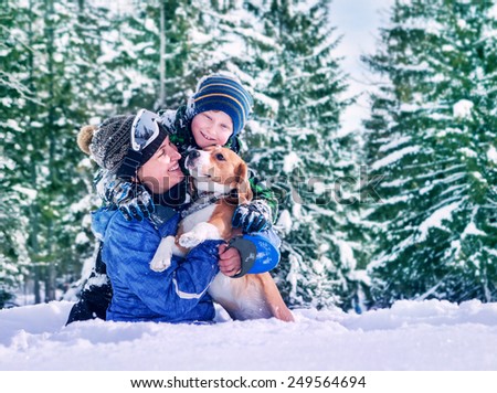 Mother with son and dog playing together in snow forest