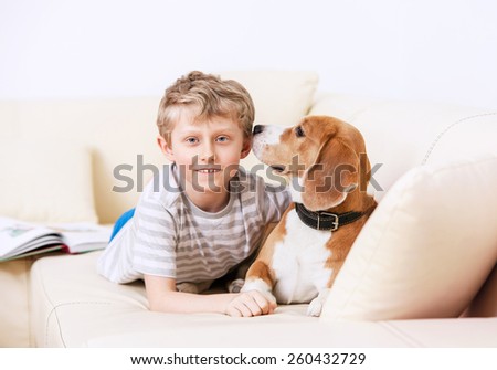 Boy and dog lying on white sofa together