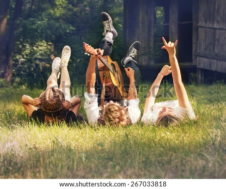 Careless teenagers lying on the green lawn with guitar