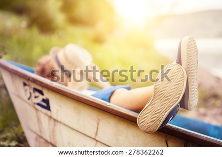 Boy lying in old boat in the lake coast close up image