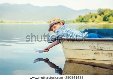 Little boy launch paper ship lying in old boat