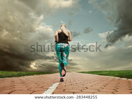 Young blonde girl evening jogging with great cloudscape