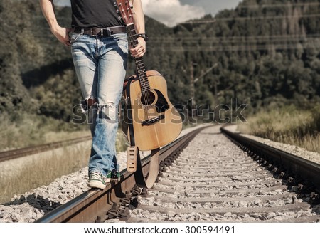 Close up image man legs in ripped denim walk on the railway
