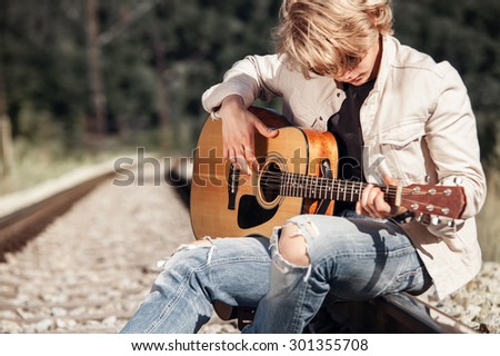 Railway blues. Young man playing on guitar on the railway