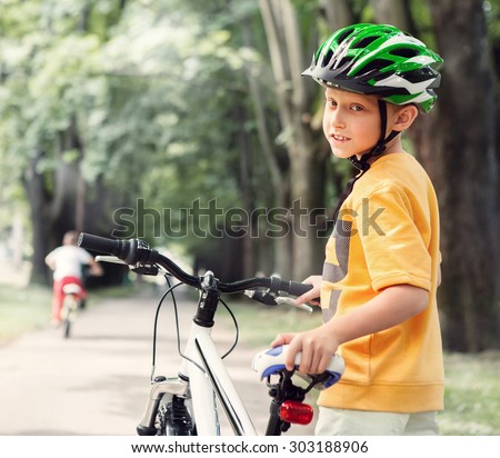 Boy in safe helmet with bicycle in city park