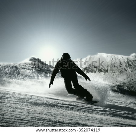 Snowboarder silhouette goes down by the high mountain ski slope