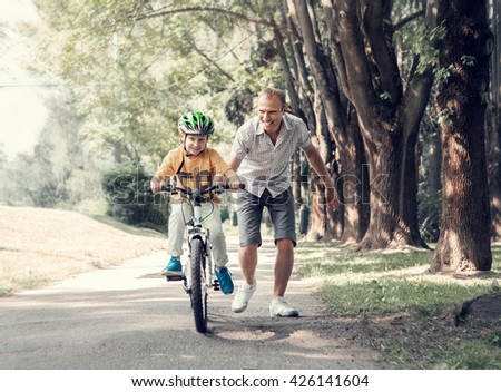 Father help his son learn to ride bicycle