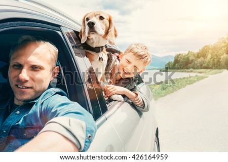 Father with son and dog look from the car window